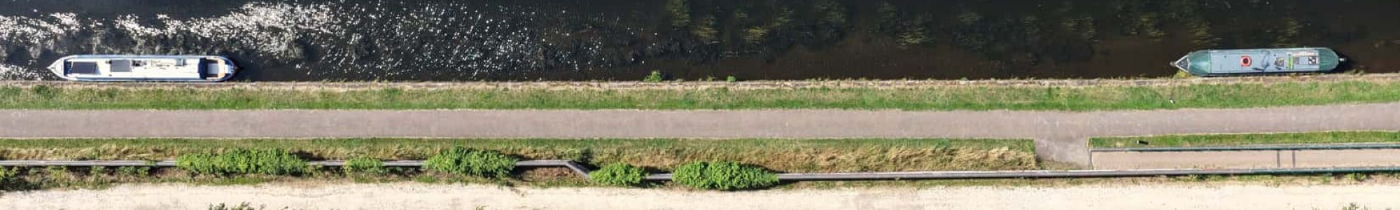 Aerial view of boats traveling along a scenic canal surrounded by lush greenery.