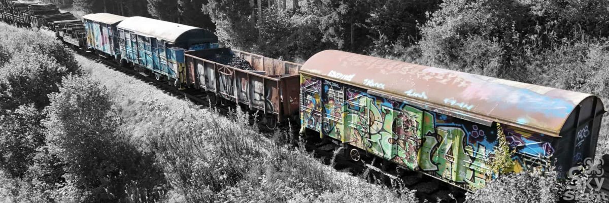 A freight train in France, taken with a drone, in black and white with colour highlights.